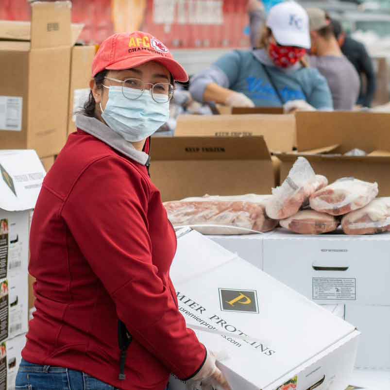 woman wearing mask carrying box of food