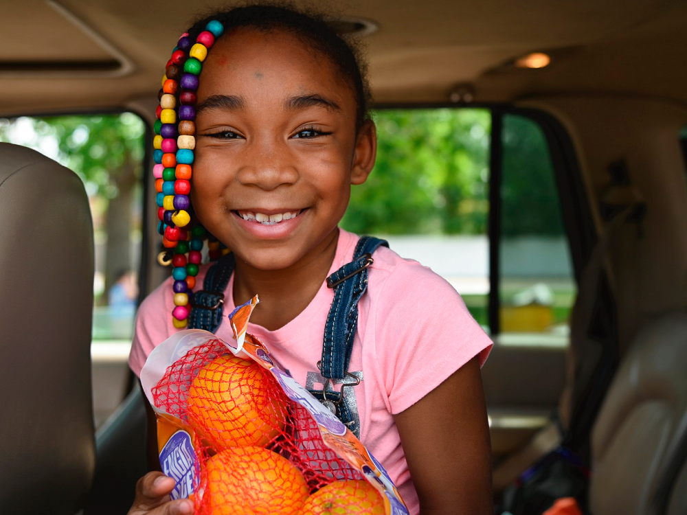 Young Girl Holding Oranges in Car