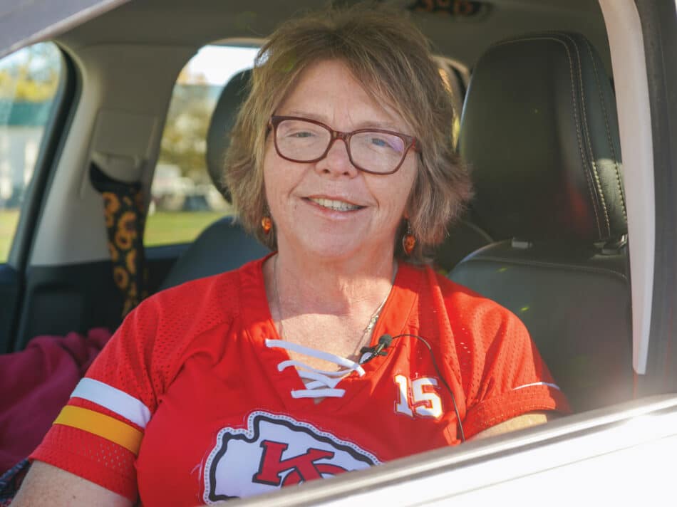 Kimberly Pipkin wearing a chiefs jersey and glasses sitting in her car at a mobile distribution.