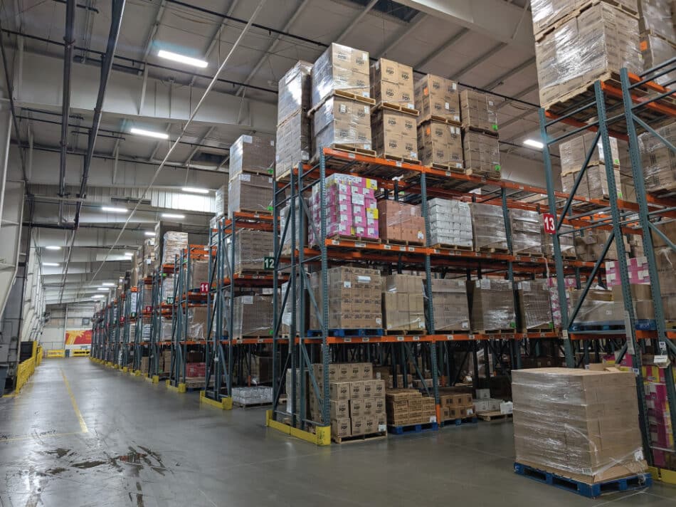 Rows of tall warehouse shelves filled with pallets of boxed food at Harvesters.